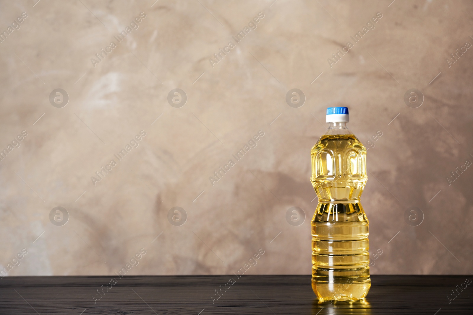 Photo of Bottle of oil on table against color background. Space for text