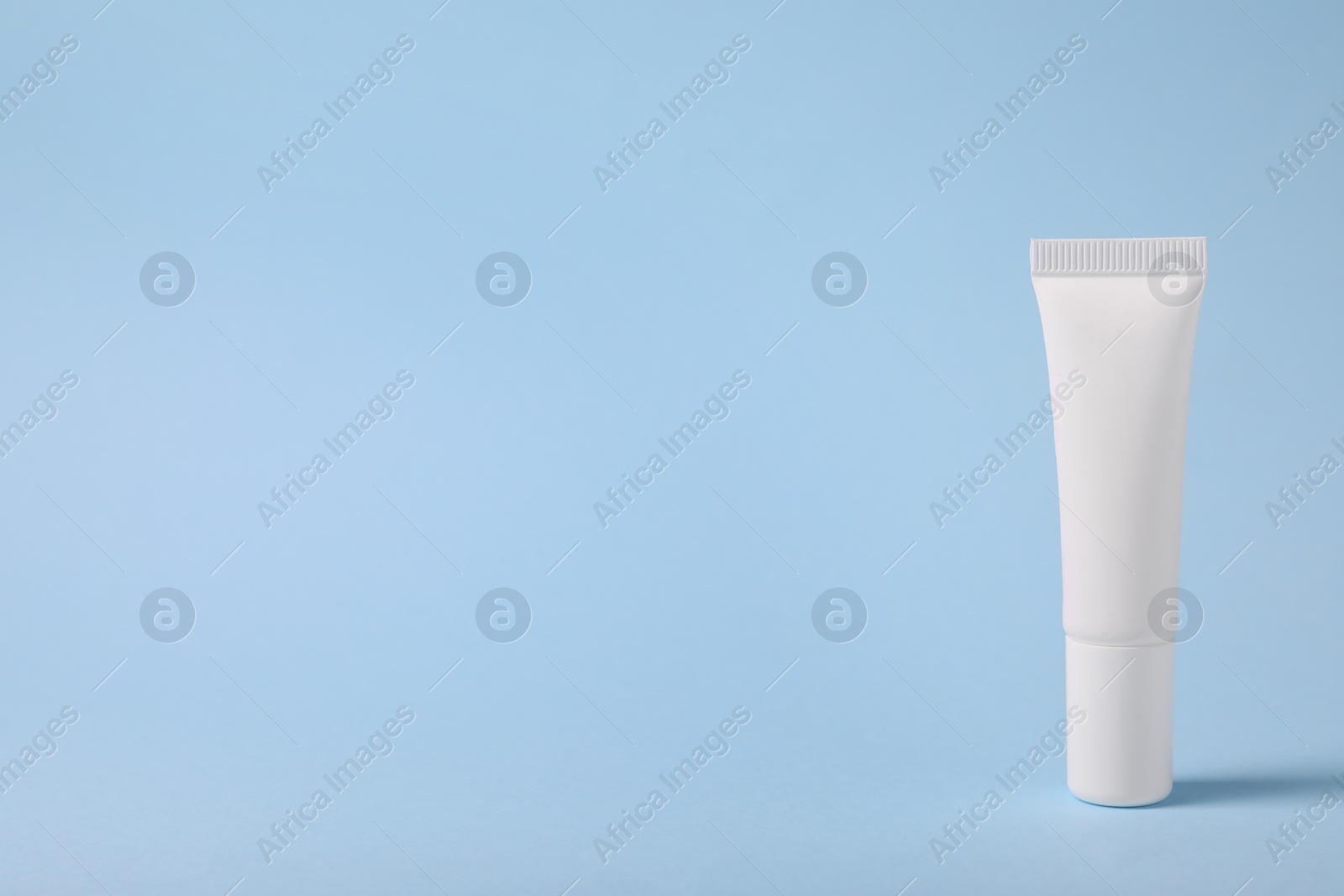 Photo of One lip balm on light blue background, space for text