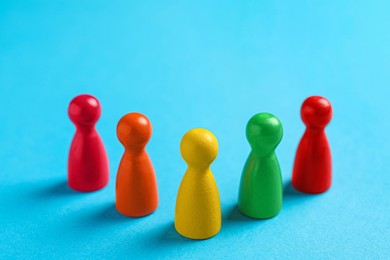 Colorful pawns on light blue background, closeup. Social inclusion concept