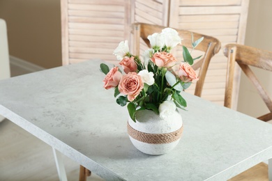 Vase with beautiful flowers as element of interior design on table in room