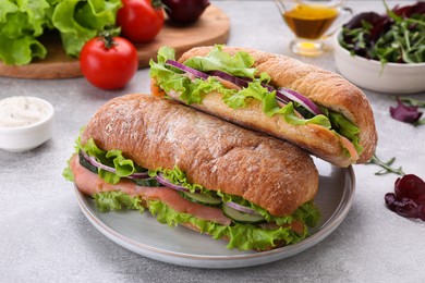 Photo of Delicious sandwiches with fresh vegetables and salmon on light gray table