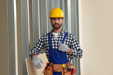 Professional builder in uniform with tool belt indoors