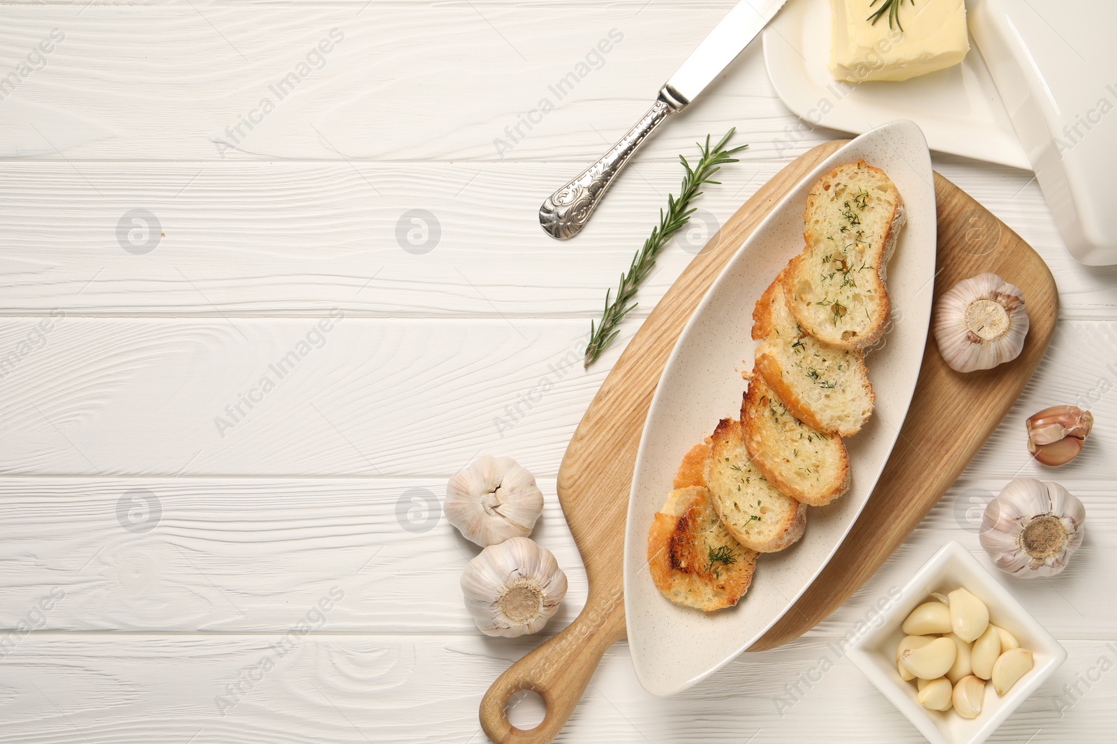 Photo of Tasty baguette with garlic and dill served on white wooden table, flat lay. Space for text