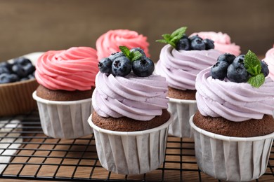Photo of Sweet cupcakes with fresh blueberries on wooden table, closeup