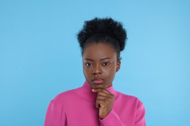 Portrait of concentrated young woman on light blue background