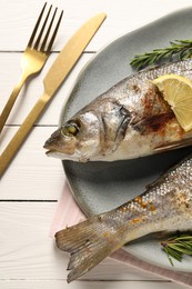 Photo of Delicious baked fish served on white wooden table, top view