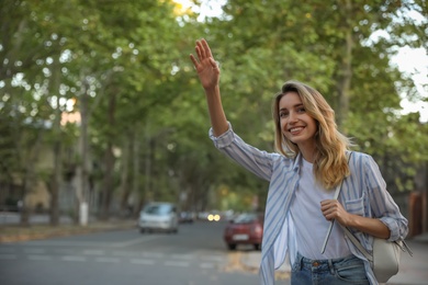 Photo of Young woman catching taxi on city street