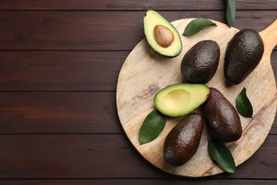 Photo of Whole and cut avocados on wooden table, flat lay. Space for text