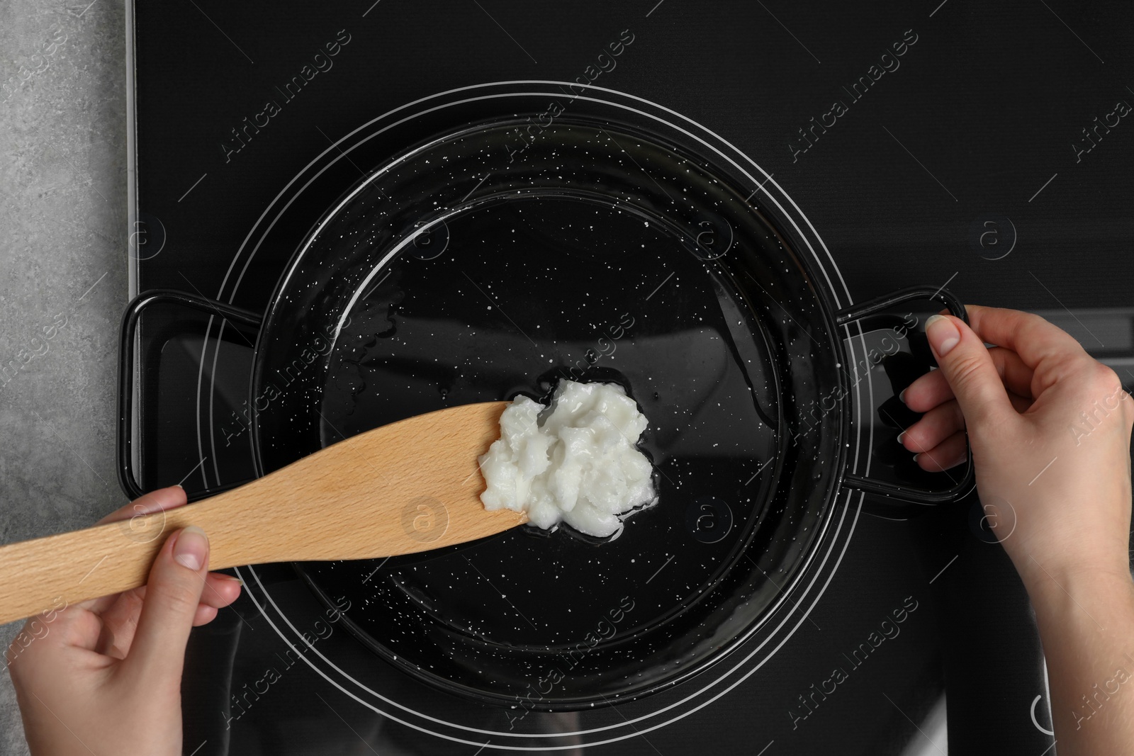 Photo of Woman cooking with coconut oil on induction stove, top view