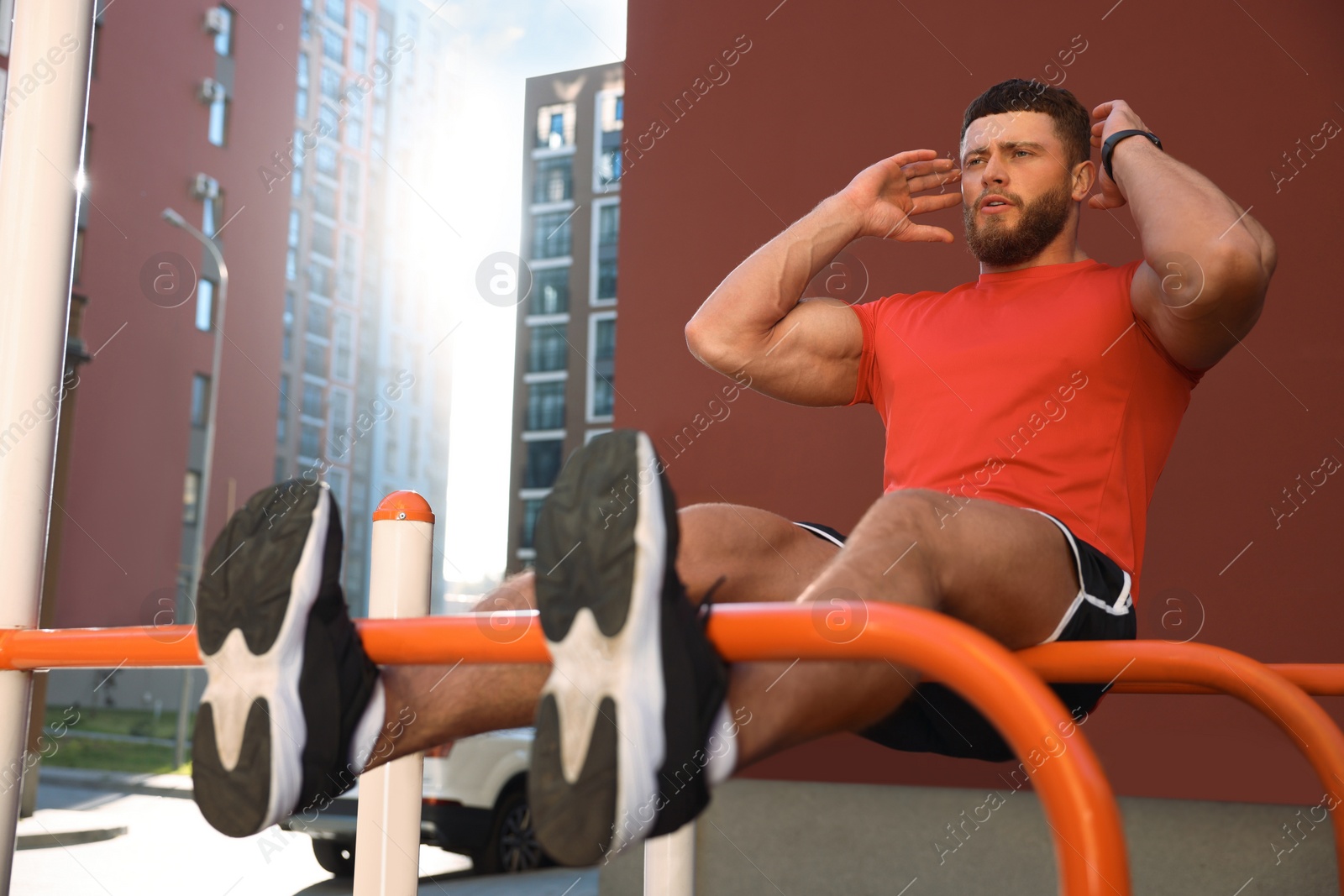 Photo of Man doing abs exercise on parallel bars at outdoor gym