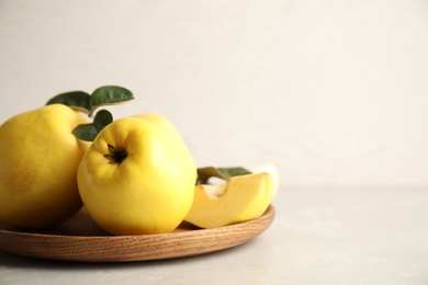 Photo of Fresh ripe organic quinces with leaves on light table. Space for text