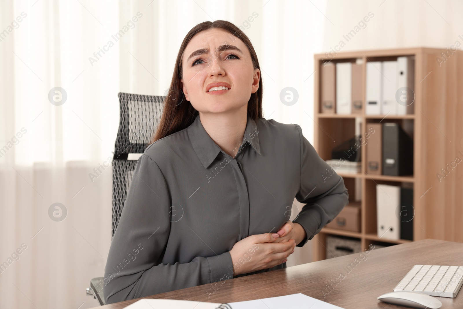 Photo of Woman having heart attack at table in office