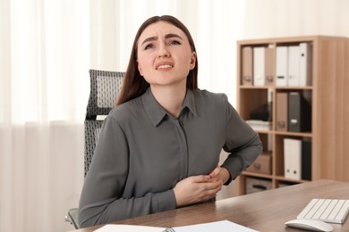 Woman having heart attack at table in office