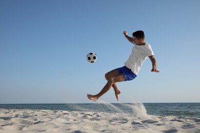 Photo of Man kicking football ball on beach near sea