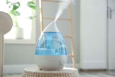 Photo of Modern air humidifier on wicker pouf indoors