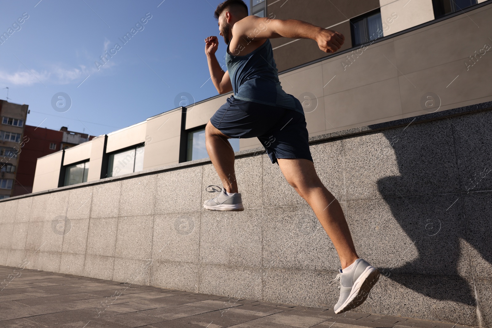 Photo of Young man running near building outdoors, low angle view. Space for text