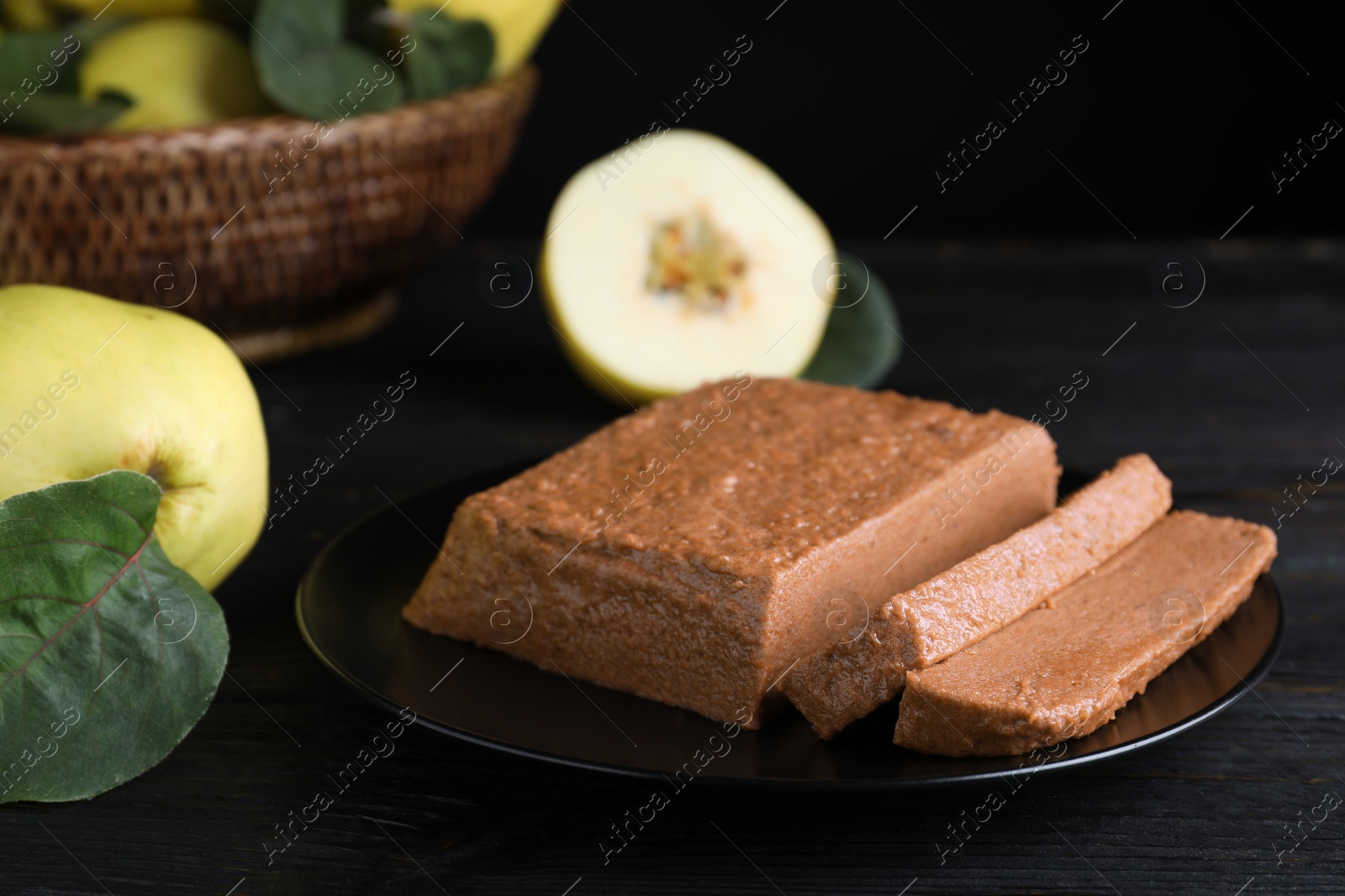 Photo of Black plate with quince paste on dark table, closeup