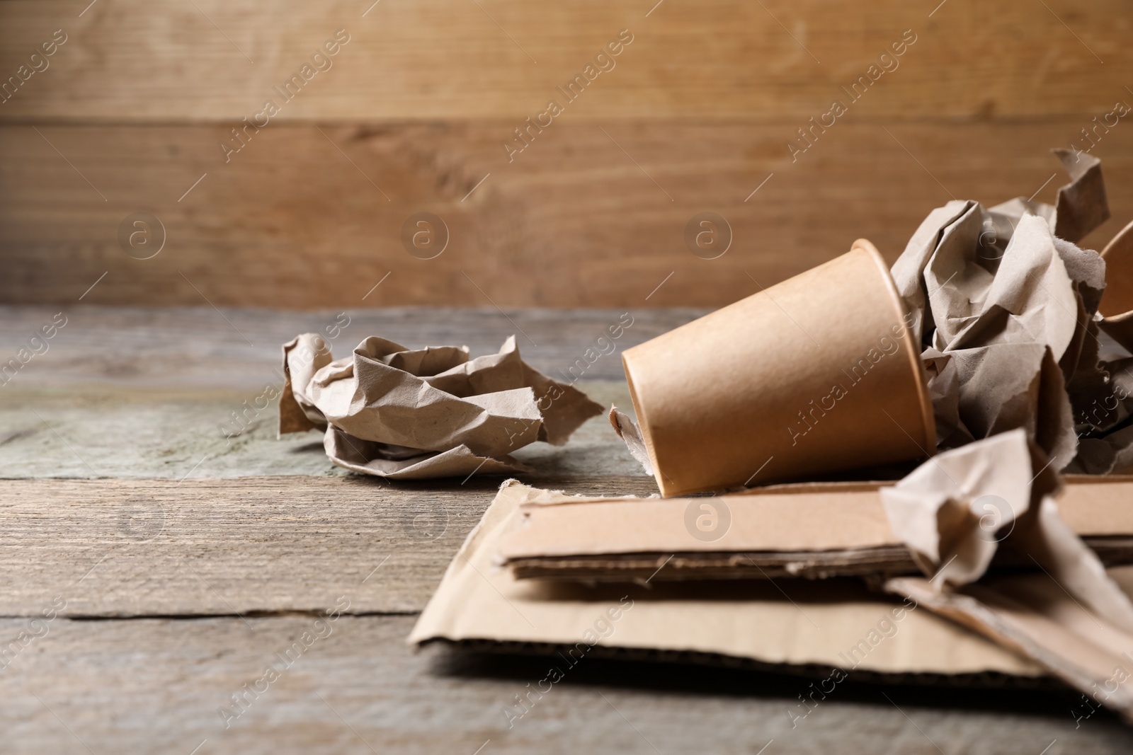 Photo of Different waste paper on wooden table, closeup. Space for text