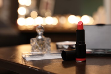 Red lipstick and other beauty products on wooden table. Makeup room