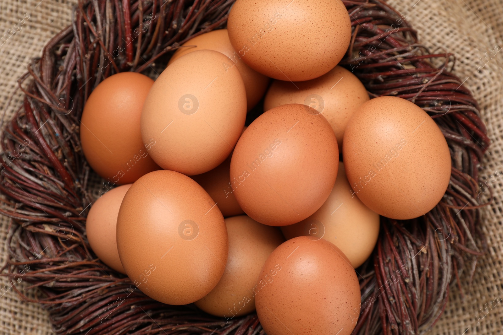 Photo of Fresh chicken eggs in nest on burlap fabric, top view