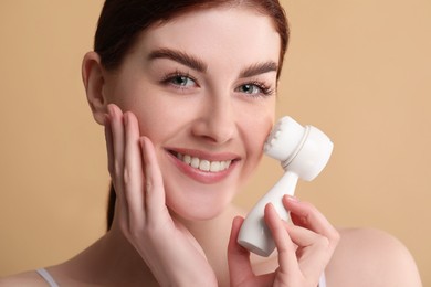 Photo of Washing face. Young woman with cleansing brush on beige background, closeup