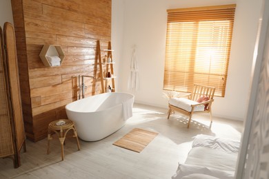 Photo of Stylish apartment interior with white bathtub and bed