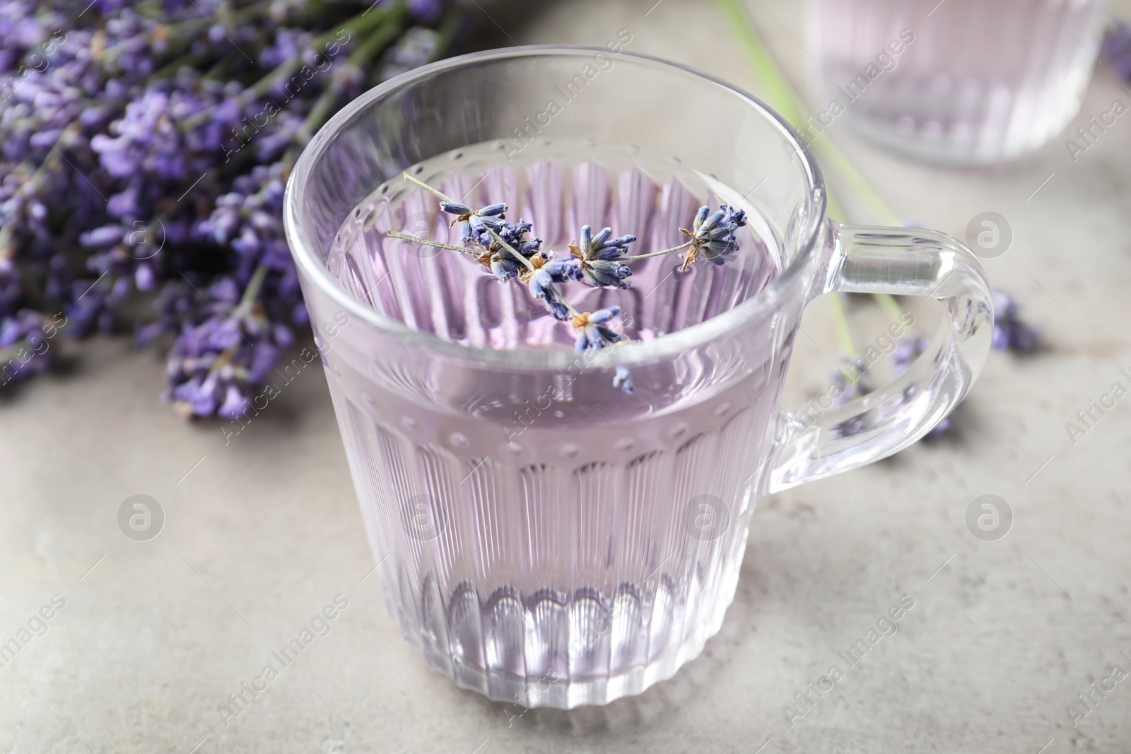 Photo of Fresh delicious drink with lavender in glass cup on grey table, closeup