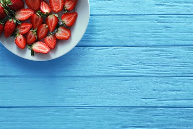 Food photography. Plate of delicious ripe strawberries on light blue wooden table, top view with space for text