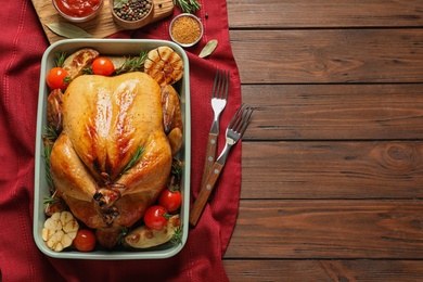 Photo of Cooked turkey with vegetables in dish on wooden background, flat lay. Space for text