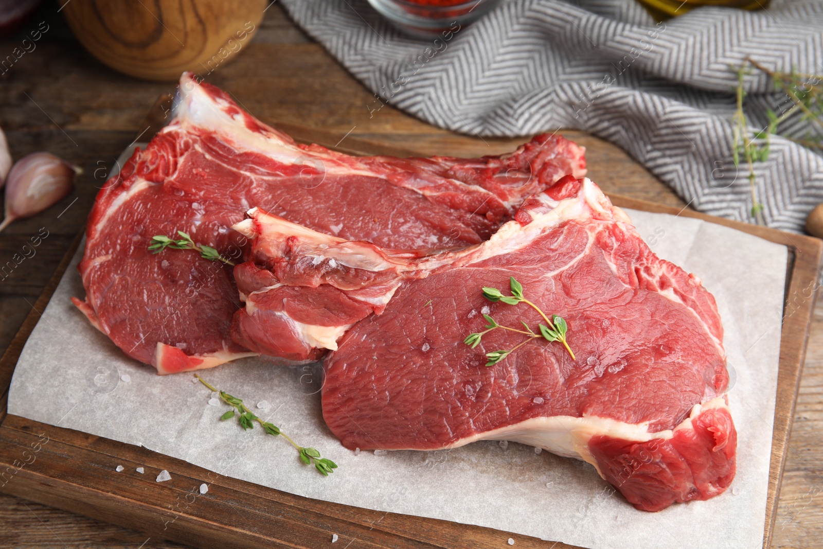 Photo of Fresh raw beef cut with thyme and salt on wooden table, closeup