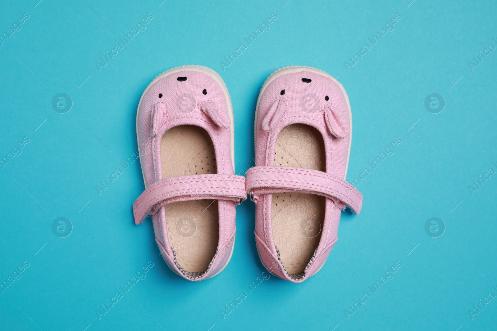 Photo of Cute baby shoes on light blue background, flat lay