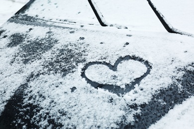 Photo of Heart drawn on car covered with snow, closeup. Space for text