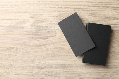 Blank black business cards on wooden table, top view. Mockup for design
