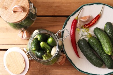 Photo of Fresh cucumbers, garlic and pepper on wooden table, flat lay. Pickling recipe