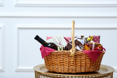 Photo of Gift set in wicker basket on golden table near white wall