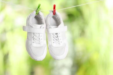 Stylish sneakers drying on washing line against blurred background