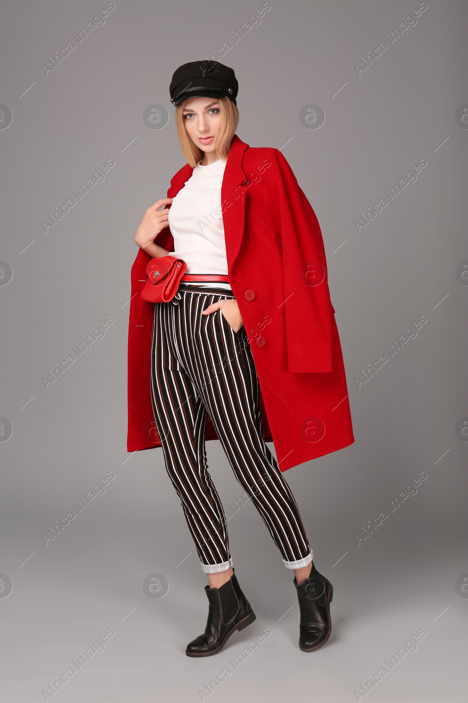 Photo of Young stylish woman in trendy shoes with bum bag on grey background