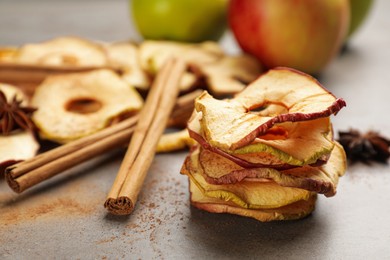 Photo of Delicious apple chips and cinnamon on grey table, closeup