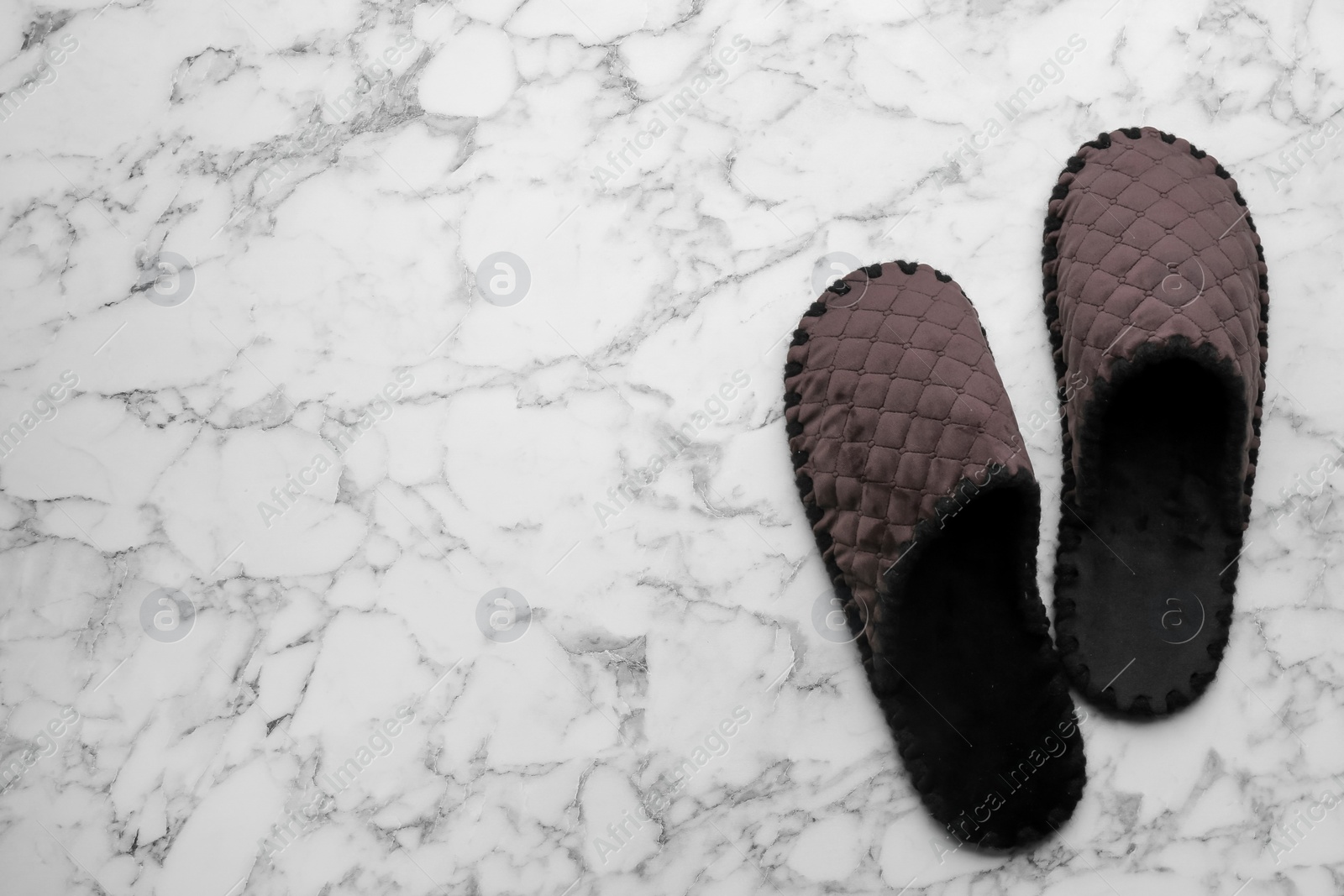 Photo of Pair of soft slippers on white marble background, flat lay. Space for text