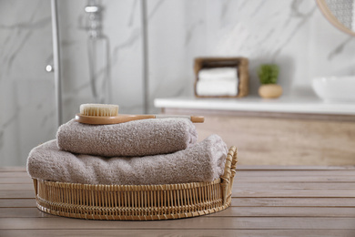 Clean towels and shower brush on wooden table in bathroom