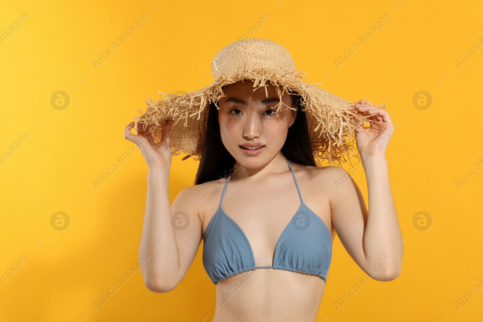 Photo of Beautiful young woman in straw hat on orange background