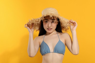 Photo of Beautiful young woman in straw hat on orange background