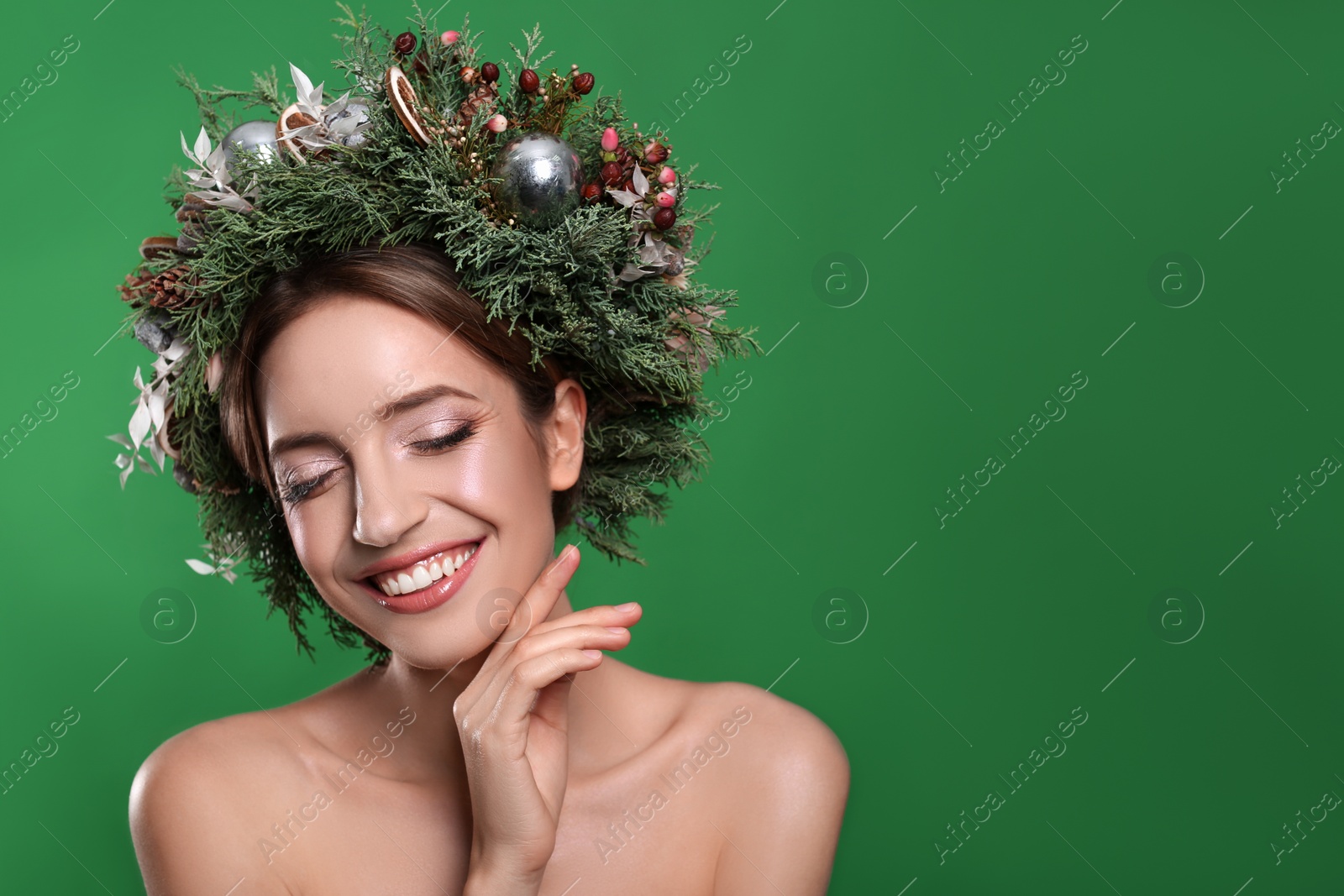 Photo of Beautiful young woman wearing Christmas wreath on green background. Space for text