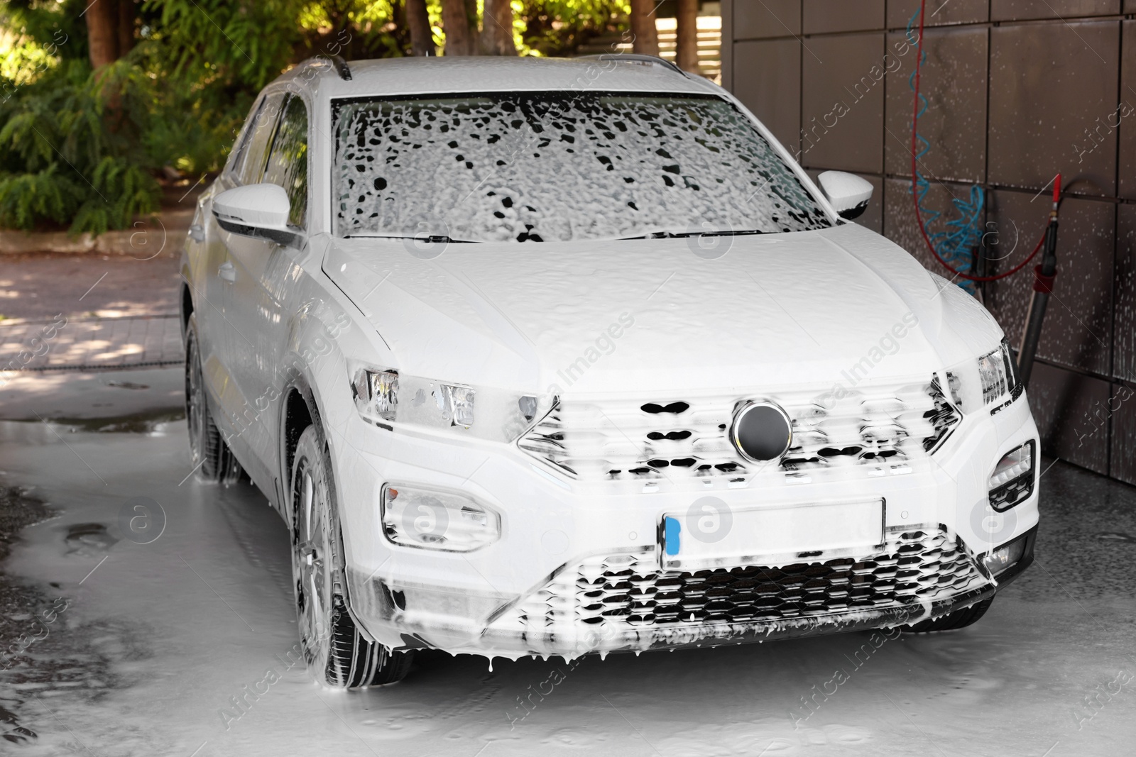 Photo of Auto covered with cleaning foam at outdoor car wash