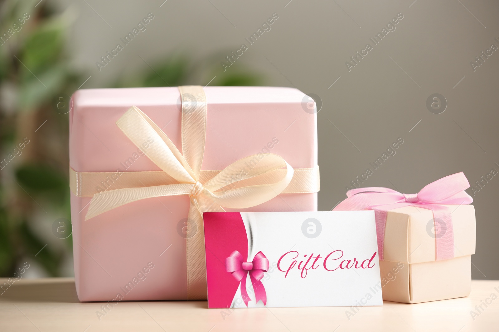 Photo of Gift card and present on table against blurred background