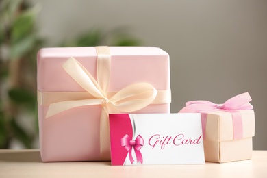 Photo of Gift card and present on table against blurred background