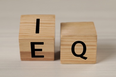 Wooden cubes with letters E, I and Q on white table