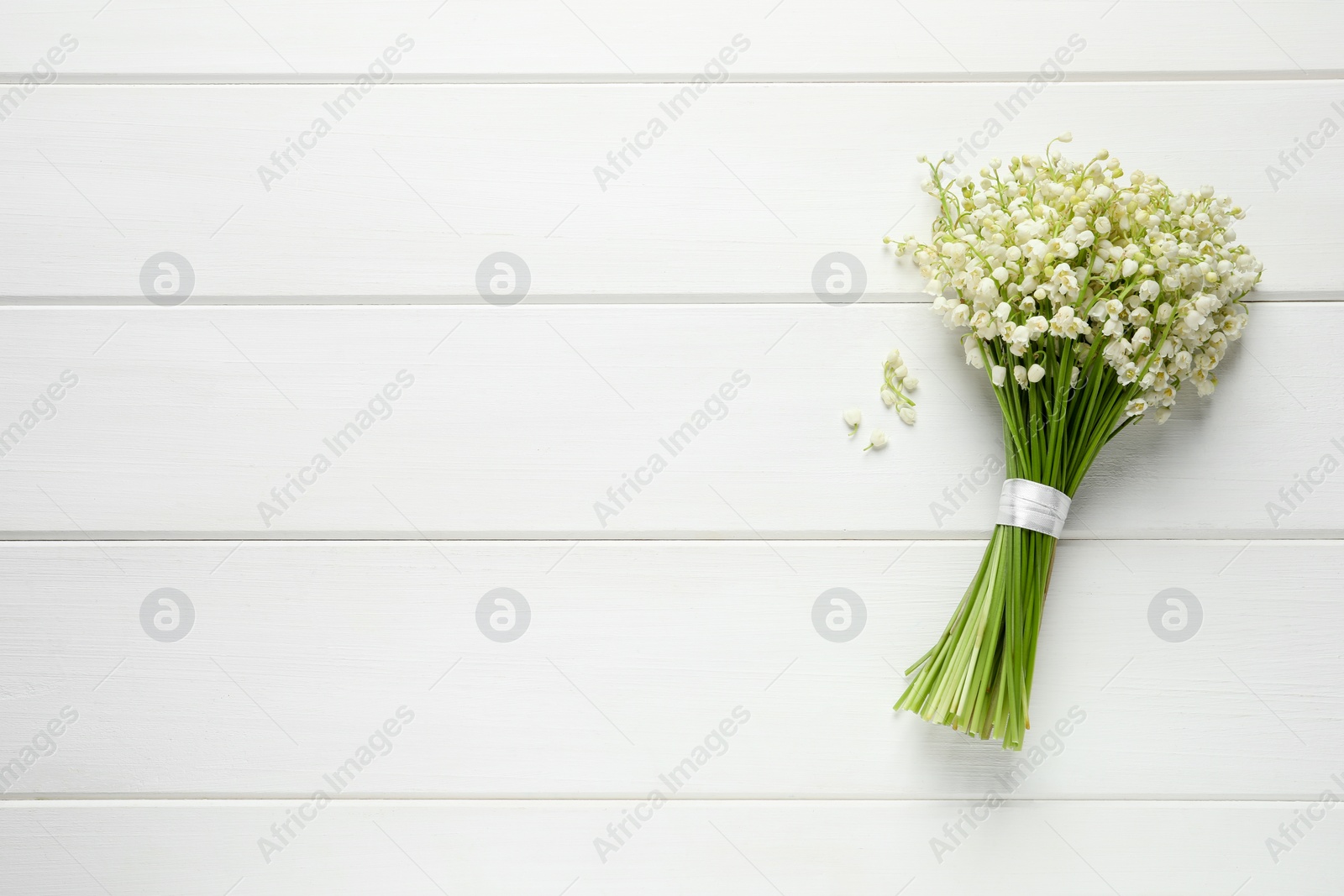 Photo of Beautiful lily of the valley bouquet on white wooden table, top view. Space for text