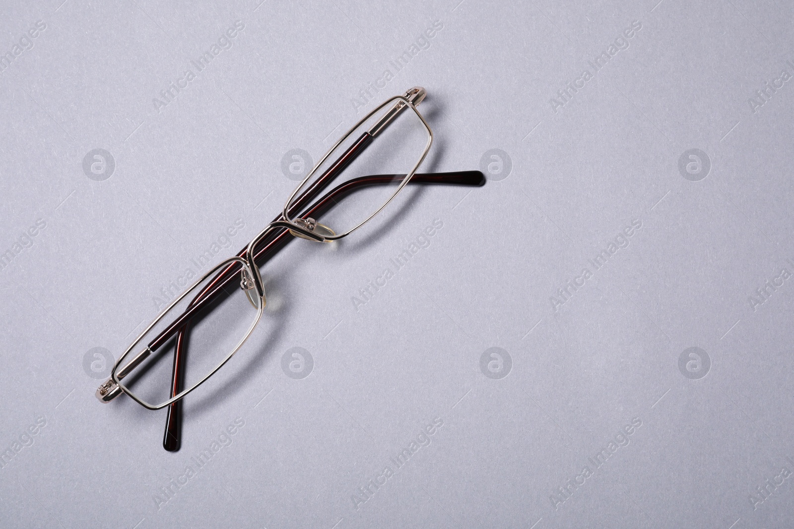 Photo of Stylish pair of glasses with metal frame on grey background, top view. Space for text