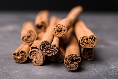 Photo of Aromatic cinnamon sticks on grey table, closeup